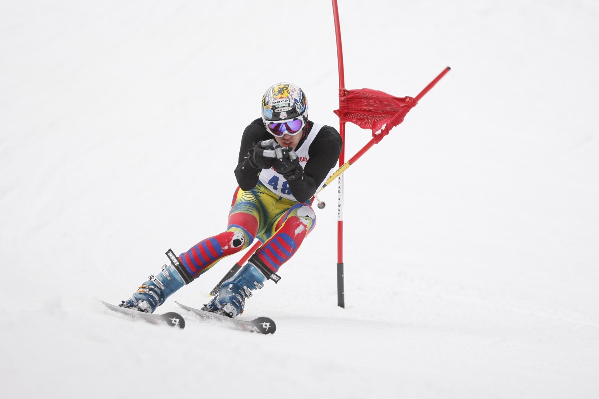 An alpine racer carving around a red giant slalom gate